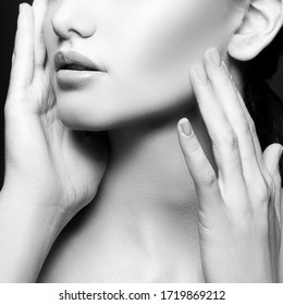 Lips, part of beauty face. Beauty Portrait of young woman touching healthy skin. Face in hands. Black background. Skincare health concept. Monochrome