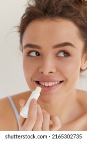 Lips Protection. Beautiful Woman With Happy Face, Sexy Full Lips Applying Lip Balm From Stick. Portrait Of Female Model With Natural Makeup. Lips Skin Care Cosmetics Concept. High Resolution 