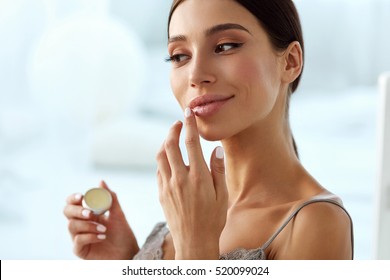 Lips Skin Care. Beautiful Woman With Beauty Face Applying Lip Balsam, Lipbalm On Full Sexy Lips. Portrait Of Smiling Female Model With Soft Skin And Natural Nude Makeup Touching Lips. High Resolution