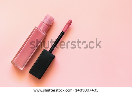 Lipstick and applicator wand on pastel pink backgrpund. Liquid lip stick open tube. Makeup cosmetic product. Top view, flat lay, copy space