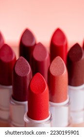 Lipsticks stand next to a triangle, close up vertical photo at pink background - Shutterstock ID 2230195901