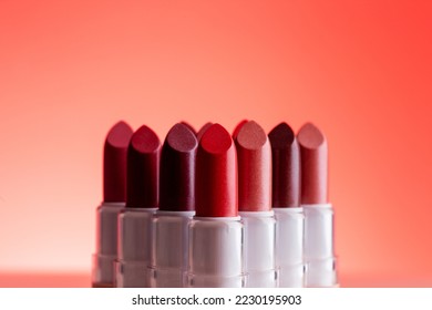 Lipsticks stand in a row, lipsticks stand next to a triangle at pink background - Shutterstock ID 2230195903