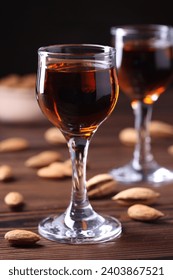 Liqueur glass with tasty amaretto and almonds on wooden table, closeup