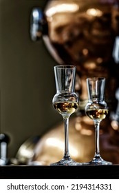 Liqueur Glasses In Front Of A Gin Distiller.