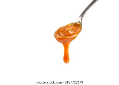 Liquid caramel on spoon. Caramel drips from the spoon. Pouring sweet caramel sauce. Texture, Close up.