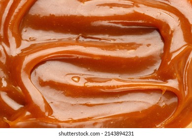 Liquid caramel syrup. Background of caramel paste. Curl of caramel. Texture Close up, top view.