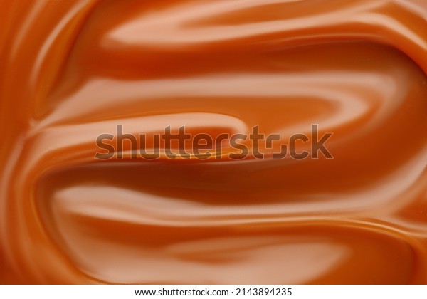 Liquid caramel syrup.\
Background of caramel paste. Curl of caramel. Texture Close up, top\
view.