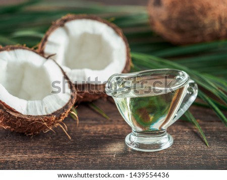 Liquid coconut MCT oil and halved coco-nut on wooden table. Health Benefits of MCT Oil. MCT or medium-chain triglycerides, form of saturated fatty acid.