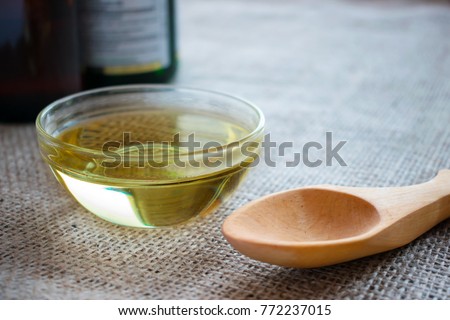 Liquid coconut MCT oil in round glass bowl with wooden spoon and bottles. Health Benefits of MCT Oil. Triglycerides, a form of saturated fatty acid.