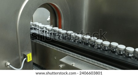 liquid filled injection glass vials moving in a row inside a medicine manufacturing company