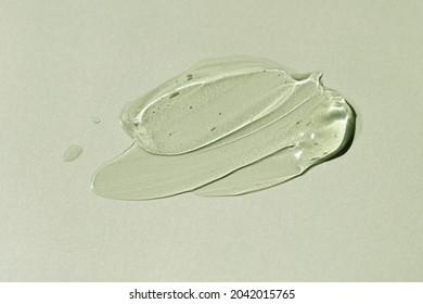Liquid gel smear isolated on grey green background. Beauty cosmetic smudge such as pure transparent aloe lotion, facial jelly serum, cleanser, shower gel or shampoo top view. - Shutterstock ID 2042015765