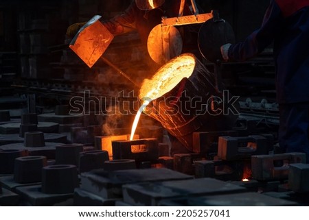 The liquid metal or cast iron poured into molds. Metal casting process with red high temperature fire in metallurgical factory. Metal part factory, foundry cast, heavy industry