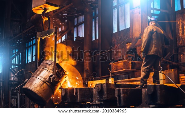Liquid metal pouring\
into molds. Metal melting in furnaces in foundry metallurgical\
plant, heavy industry