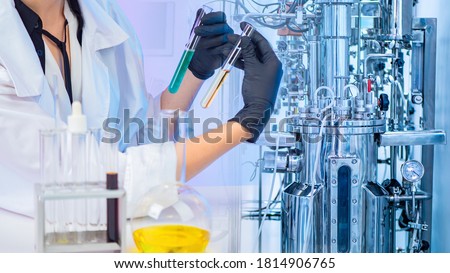 Liquid obtained in the fermentation process. Microbiologist with test tubes in his hands. Chemical laboratory equipment. Laboratory bioreactor for the production of vaccines. Pharmacology.