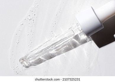 Liquid oil serum drop in pipette isolated on white background. Retinol, aha, bha acid, collagen skincare fluid, photo with shallow depth of field. Gold essence in dropper for beauty treatment. - Shutterstock ID 2107325231