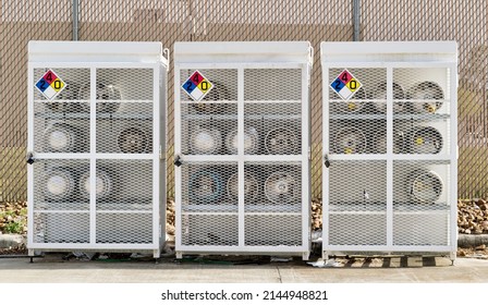 Liquid Petroleum gas cylinders stored horizontally in a metal safety cage with NFPA warning signs on the closed doors, front view outside. - Shutterstock ID 2144948821