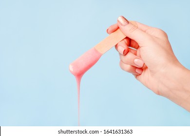 liquid pink pearl wax or sugar paste for depilation drains from the stick on blue background. The concept of depilation, waxing, sugaring smooth skin without hair, banner, copy space - Shutterstock ID 1641631363