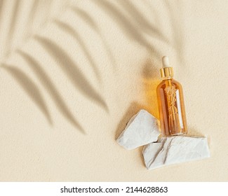 Liquid Product Package In Glass Bottle On Stone Stand, Fine Sand Background With Palm Leaf Shadows. Cosmetics Mock Up. Japanese Zen Garden With Rounds On Sand. Facial Cosmetics, Top View