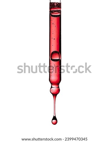 Liquid red oil serum drop in pipette isolated on white background. Peeling, aha acid, collagen skincare fluid, close up photo with shallow depth of field. Transparent crimson essence in dropper.