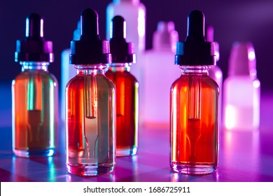 Liquids For Refilling Electronic Cigarettes Close-up. Vials Of Colored Liquids On The Table. Vaping. Smoking Electronic Cigarettes. Bottles With Pipettes Inside. E-cigarette. VAPE Shop.