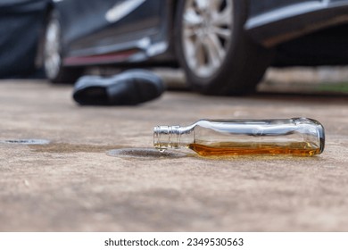 Liquor Alcohol Bottle fell on The Floor with car and shoe background.don't drink and drive concept.
