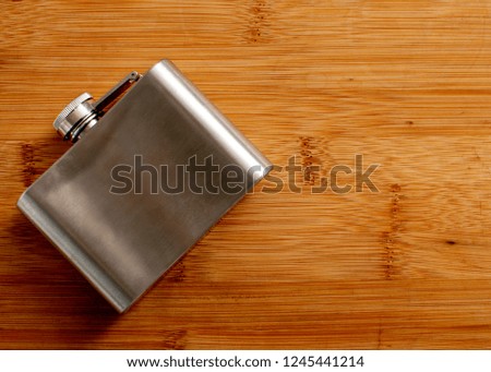 Liquor flask made of metal on a wooden background.