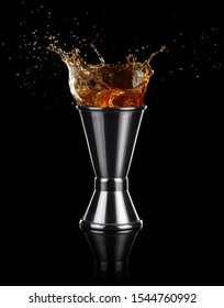 Liquor Splashing Out Of A Jigger Isolated On Black Background