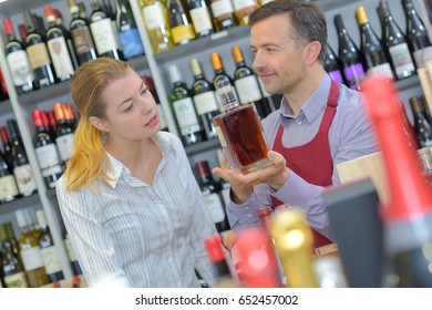 Liquor Store Worker Showing Bottle To Customer