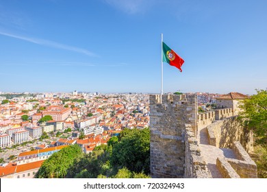 Lisbon aerial view cityscape with Portugal flag waving on ancient fortress wall of Sao Jorge Castle, at Moorish castle on highest hill in Alfama. Lisbon Castle is a popular tourist attraction.