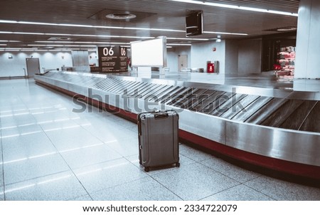 Lisbon Airport; Selective focus on a single bag in the luggage claim area, standing out against the grey floor. The indoor setting with white lights adds to the atmosphere