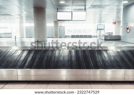 Lisbon Airport; Vertical shot; Selective focus on a single bag in the luggage claim area, standing out against the grey floor. The indoor setting with white lights adds to the atmosphere