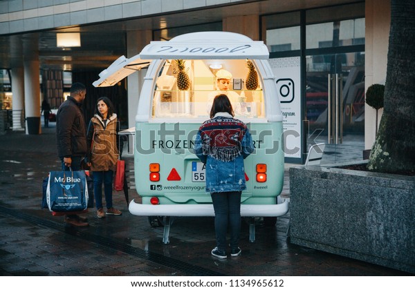 Lisbon, April 23, 2018: People buy frozen\
yogurt or ice cream from a street vendor next to fashion outlet\
called Freeport. Street food and mobile\
commerce