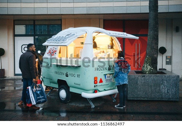 Lisbon, April 23, 2018: People buy frozen\
yogurt or ice cream from a street vendor next to fashion outlet\
called Freeport. Street food and mobile\
commerce