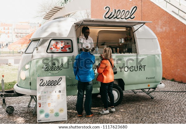 Lisbon, June 18,\
2018: People buy frozen yogurt or ice cream from a street vendor.\
Street food and mobile\
commerce