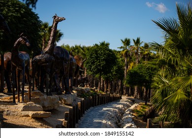 Lisbon, Portugal: 09/08/2020: Hiding part of the Buddha Garden with the african and wild animals sculptures (crocodile, giraffe, snake, monkey) in brass material.  Buddha Eden, asian style garden.