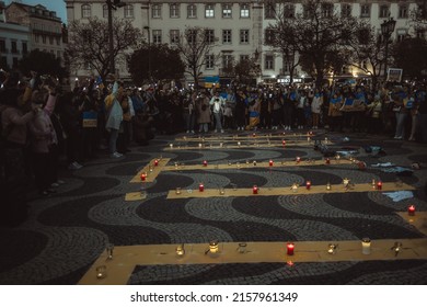 Lisbon, Portugal - April 20, 2022: a night protest rally dedicated to saving the Ukrainian city of Mariupol; burning candles in memory of the dead; people shine their cell phone flashlights up