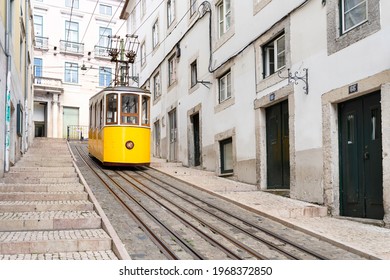 LISBON, PORTUGAL, APRIL 30, 2021: Yellow Elevator Going Up The Slope Of One Of The Most Typical Neighborhoods In The City Of Lisbon In Portugal
