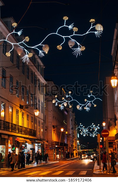 LISBON, PORTUGAL - December, 12, 2017: People and\
cars in Lisbon\'s downtown during Christmas festive time,\
illuminated buildings at\
night