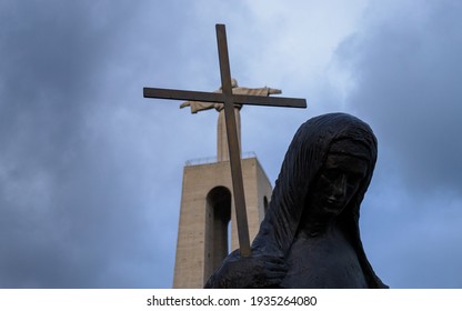 Lisbon, Portugal. December 2020. Sanctuary of Christ the King. Overlap of the cross of the Virgin statue with the statue of Jesus in the background. Juxtaposition from below. Layering effect