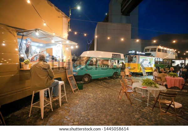 LISBON, PORTUGAL: Fast food\
trucks parked at urban area and hungry people having late dinner\
outdoor on 17 May, 2019. Portuguese language has 250 million total\
speakers