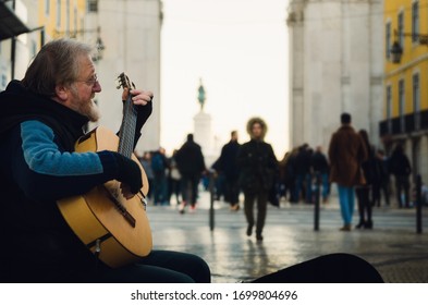 LISBON, PORTUGAL - FEBRUARY 3, 2019: Dark Moody Portait Of An Old Man Street Performer Playing Guitar In Winter On Rua Augusta, Main Shopping Street Of Lisbon, Portugal, On February 3, 2019