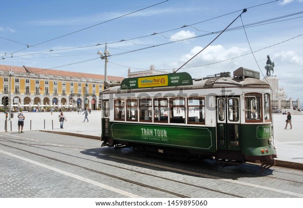 LISBON,\
PORTUGAL: Historical tour tram driving past historical squaare\
under blue sky at bright day on 17 May, 2019. Portuguese language\
has 250 million total speakers around the\
world