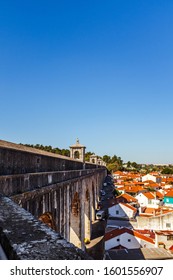 LISBON, PORTUGAL - OCTOBER 10, 2019: Águas Livres Aqueduct And Private Houses With Cars Parked Ar The Base Of Aqueduct.