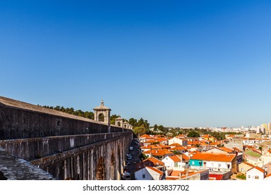 LISBON, PORTUGAL - OCTOBER 10, 2019: Águas Livres Aqueduct And Private Houses With Cars Parked Ar The Base Of Aqueduct.