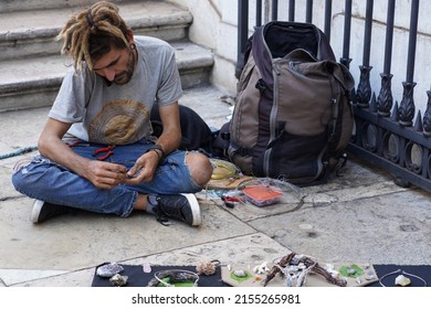 Lisbon, Portugal - October 24, 2021: A street artist with a rasta haircut sells handmade jewelry on the street