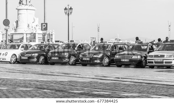 LISBON, PORTUGAL,\
on June 22, 2017. Numerous cars of the taxi expect passengers on\
the river bank of Tejo 