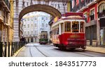 Lisbon, Portugal. Vintage red retro tram on narrow bystreet tramline in Alfama district of old town. Popular touristic attraction of Lisboa city. Public tramways trasport.