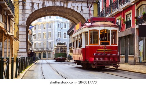 Lisbon, Portugal. Vintage red retro tram on narrow bystreet tramline in Alfama district of old town. Popular touristic attraction of Lisboa city. Public tramways trasport.