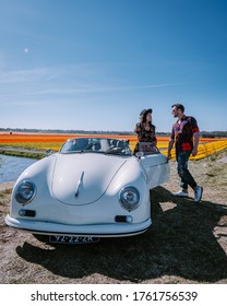 Lisse Netherlands ,. couple doing a road trip with a old vintage sport car White Porsche 356 Speedster, Dutch flower bulb region with tulip fields, colorful tulip fields - Shutterstock ID 1761756539