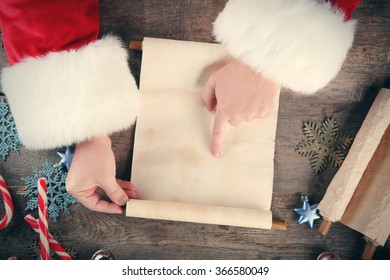 A List Of Christmas Wishes In Santa Claus Hands On Wooden Background